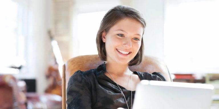 Mujer sonriente con chaqueta de cuero frente a su laptop