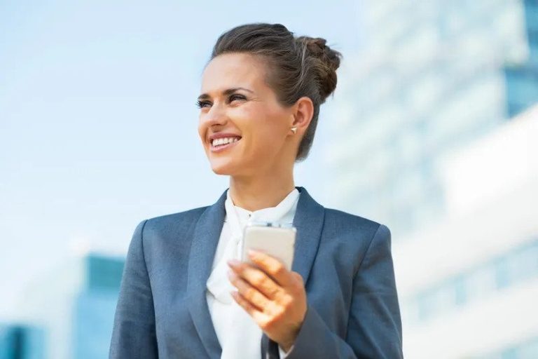 Mujer profesional sonriente con traje gris y teléfono móvil, ejemplo de asesoría de imagen profesional