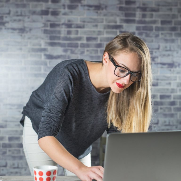 Emprendedora con lentes inclinada sobre su laptop