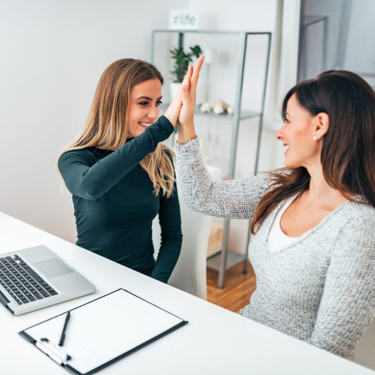 Dos mujeres profesionales chocando las manos en una oficina