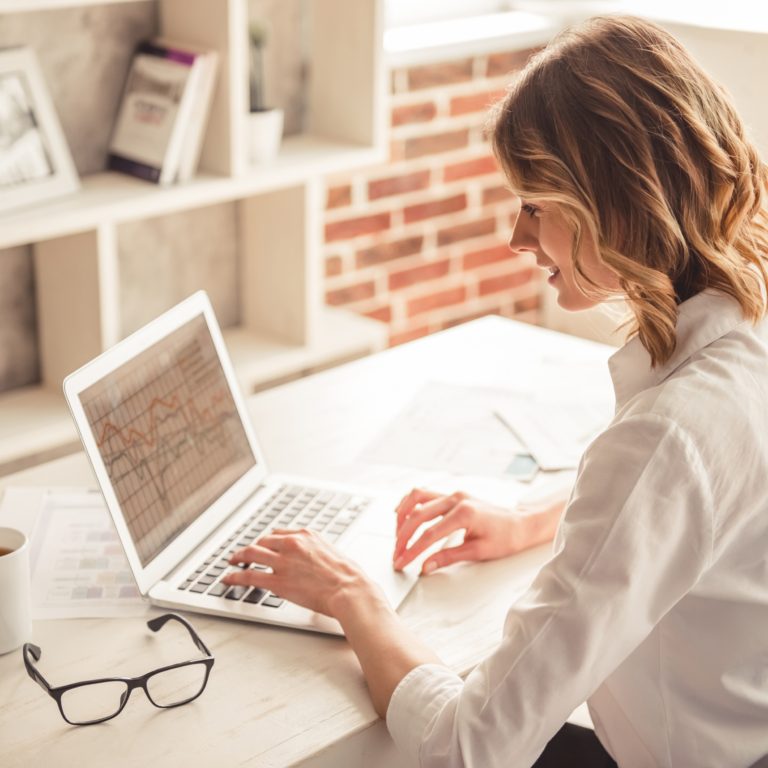 Mujer ejecutiva trabajando con su laptop en un escritorio blanco