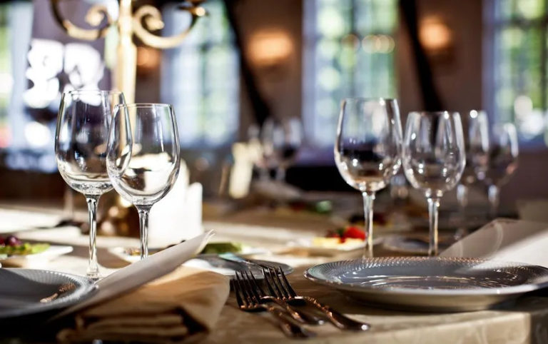 Mesa de restaurante elegante con copas, platos y cubiertos bien dispuestos