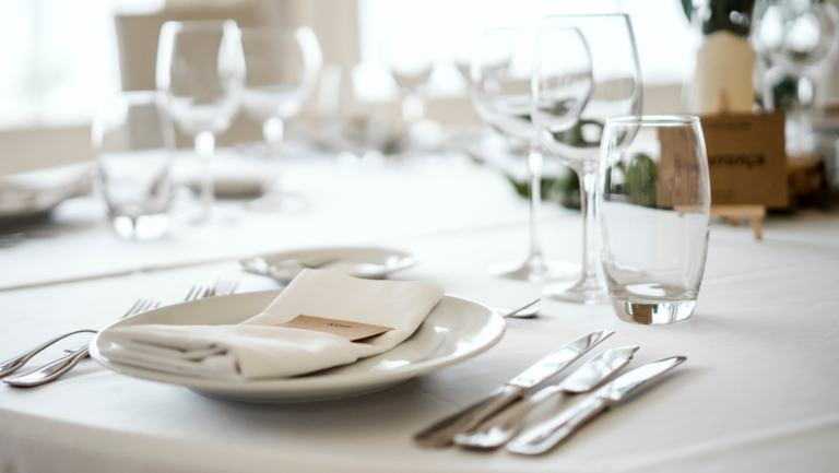 Mesa elegante con plato, servilleta, cubiertos y copas para una clase de etiqueta de mesa