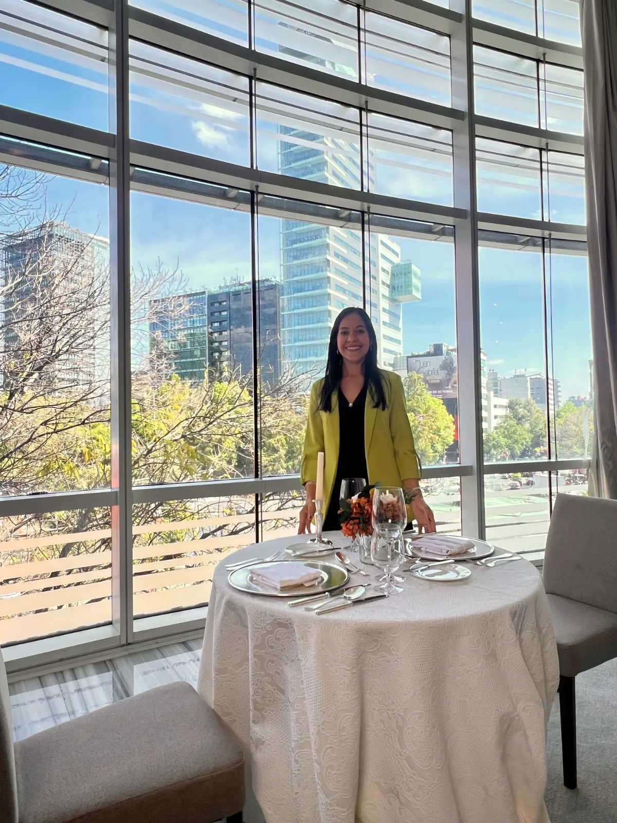 Eunice Arroyo junto a una mesa redonda con mantel blanco preparada para un taller de etiqueta de mesa